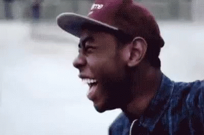 a man wearing a baseball cap and a denim jacket is smiling .