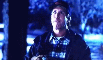 A Man Wearing A Baseball Cap And A Plaid Shirt Is Standing In The Dark Looking Up . GIF