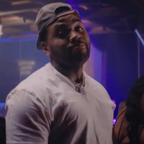 A Man Wearing A Baseball Cap And A White Shirt Is Looking At The Camera GIF