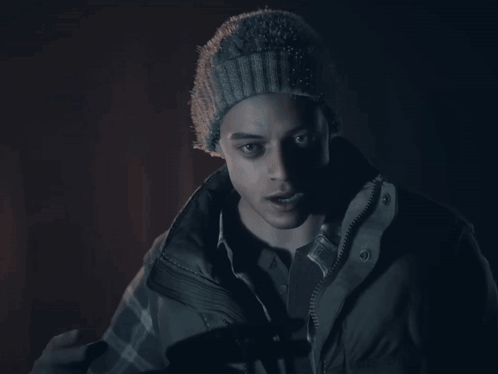 A Man Wearing A Beanie And A Jacket Is Giving The Peace Sign GIF