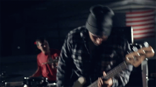 A Man Wearing A Beanie Is Playing A Guitar GIF