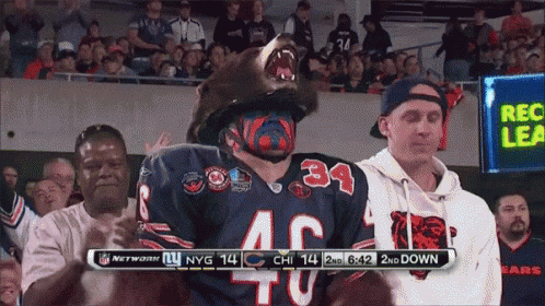 A Man Wearing A Bear Mask Is Standing In Front Of A Scoreboard That Says Nfl Network GIF