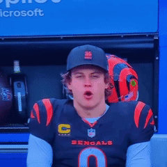 A Man Wearing A Bengals Jersey Is Sitting In Front Of A Microsoft Advertisement GIF