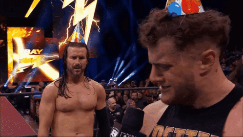 Man In Birthday Hat Talking To Another Man GIF