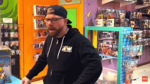 A Man Wearing A Black Aew Hoodie Is Standing In A Store GIF