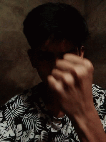 a man wearing a black and white floral shirt looks down