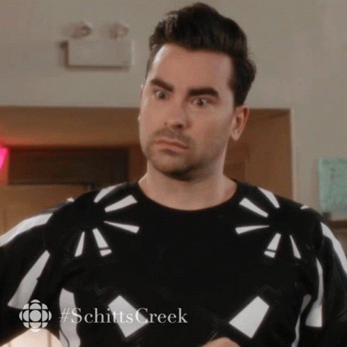 A Man Wearing A Black And White Sweater With #Schitts Creek On The Bottom GIF