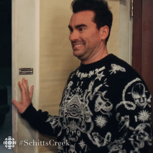A Man Wearing A Black And White Sweater With The Word Schitts Creek On The Bottom GIF