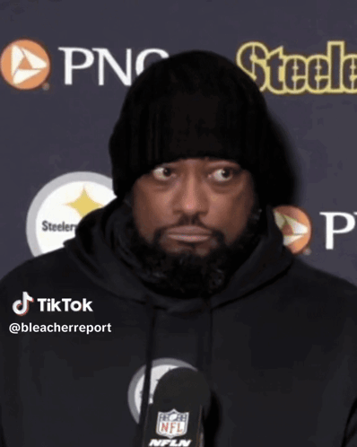 A Man Wearing A Black Beanie And A Black Hoodie Is Talking Into A Microphone GIF