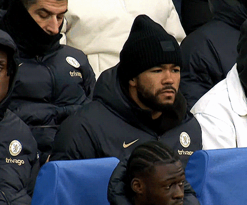 A Man Wearing A Black Beanie Is Sitting In A Stadium Watching A Game GIF