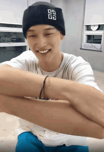a man wearing a black beanie with the letter g on it smiles