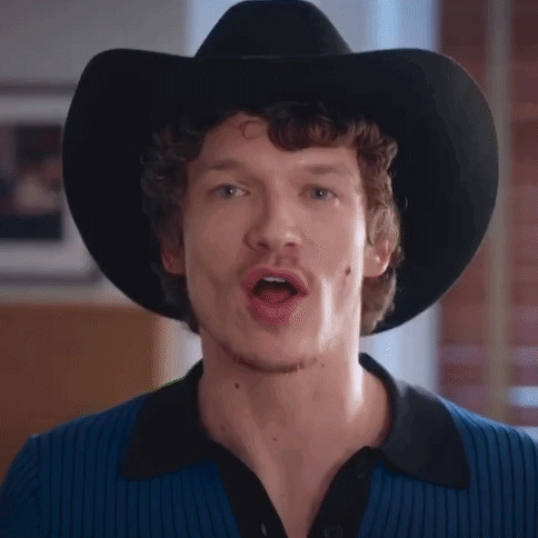 A Man Wearing A Black Cowboy Hat And A Blue Shirt Is Singing . GIF