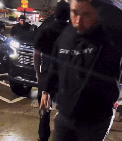 a man wearing a black givenchy shirt is walking