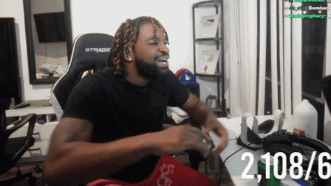 A Man Wearing A Black Gtracing Chair Is Sitting At A Desk GIF