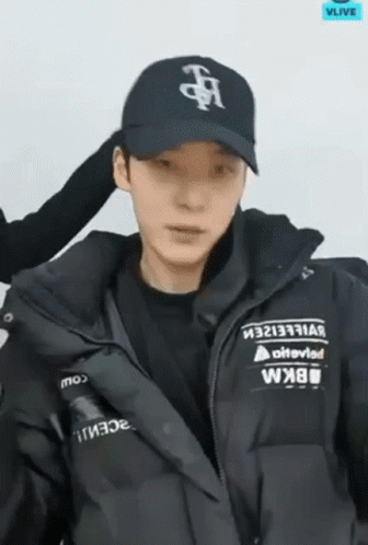A Man Wearing A Black Hat And A Black Jacket Is Looking At The Camera . GIF