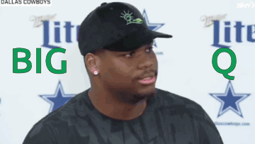 A Man Wearing A Black Hat And A Black Shirt Is Standing In Front Of A Sign That Says Dallas Cowboys GIF