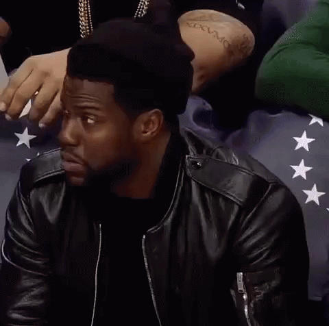 A Man Wearing A Black Hat And A Leather Jacket Is Sitting In A Crowd . GIF