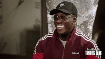 A Man Wearing A Black Hat And Sunglasses Is Smiling . GIF