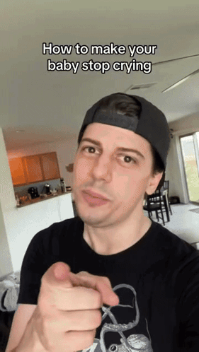 A Man Wearing A Black Hat Is Pointing At The Camera With The Caption " How To Make Your Baby Stop Crying " Above Him GIF