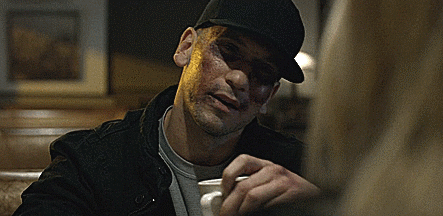 A Man Wearing A Black Hat Is Sitting At A Table Holding A Cup Of Coffee GIF