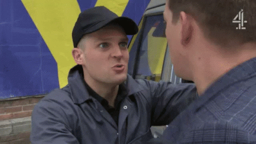 A Man Wearing A Black Hat Is Talking To Another Man In Front Of A Van That Says 4 GIF