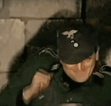 A Man Wearing A Black Hat With A Bird On It GIF