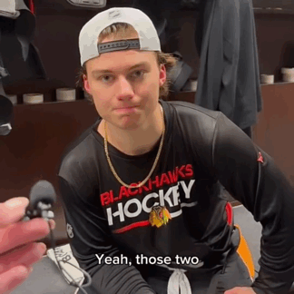 A Man Wearing A Black Hawks Hockey Shirt GIF