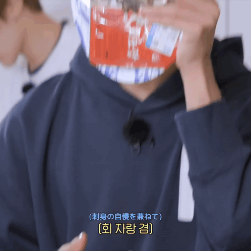 A Man Wearing A Black Hoodie Is Holding A Bottle Of Soda In Front Of His Face GIF