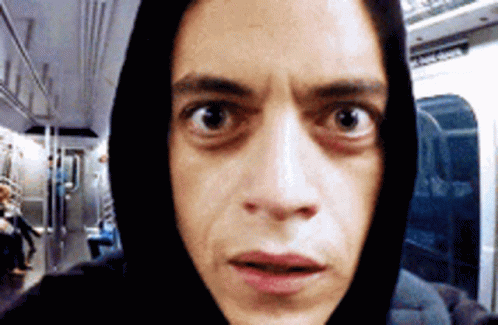 A Man Wearing A Black Hoodie Is Looking At The Camera With A Surprised Look On His Face GIF