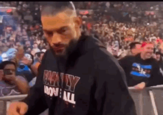 a man wearing a black hoodie is walking in front of a crowd .
