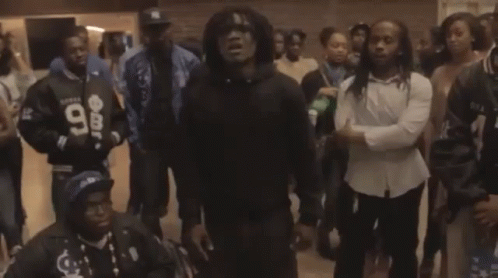 A Man Wearing A Black Hoodie With The Number 98 On It Stands In A Crowd Of People GIF