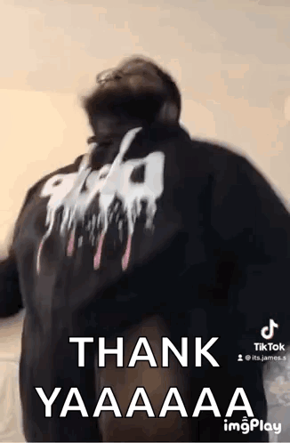 A Man Wearing A Black Hoodie With The Words `` Thank Yaaaa '' On The Back Is Dancing . GIF