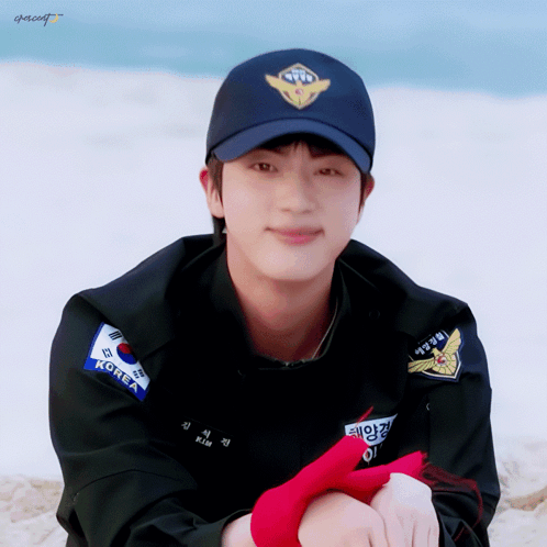 A Man Wearing A Black Jacket And A Blue Hat With The Word Korea On It GIF