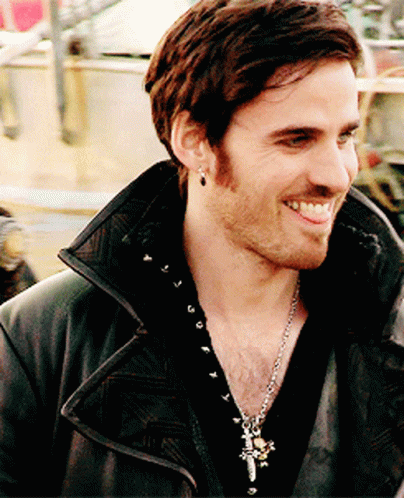 A Man Wearing A Black Jacket And A Cross Necklace Smiles For The Camera GIF