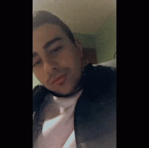 A Man Wearing A Black Jacket And A White Shirt Is Looking At The Camera GIF