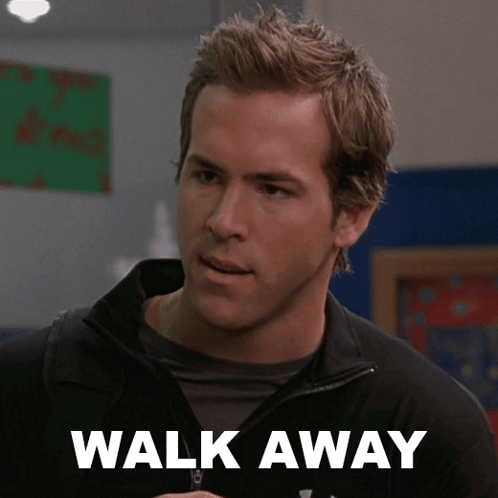 A Man Wearing A Black Jacket Stands In Front Of A Sign That Says " Walk Away " GIF