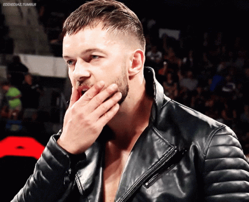 A Man Wearing A Black Leather Jacket Covers His Mouth With His Hand GIF