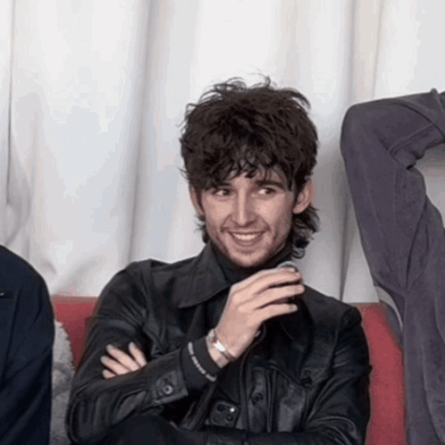 A Man Wearing A Black Leather Jacket Is Smiling With His Arms Crossed GIF