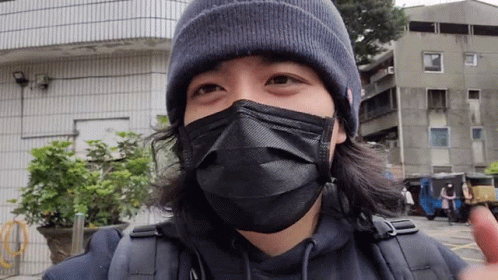 A Man Wearing A Black Mask And A Beanie Is Looking At The Camera GIF
