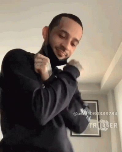 A Man Wearing A Black Mask Is Dancing In A Room With Triller Written On The Bottom Right GIF