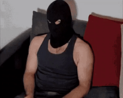A Man Wearing A Black Mask Is Sitting On A Couch . GIF