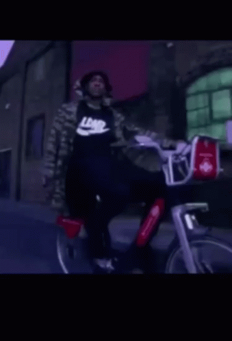 A Man Wearing A Black Nike Shirt Rides A Bike GIF