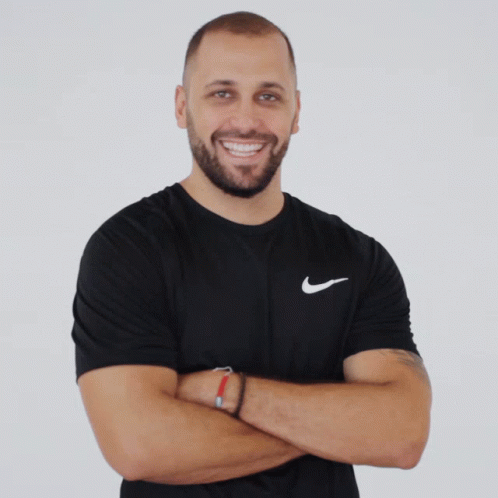 A Man Wearing A Black Nike Shirt With His Arms Crossed Smiles For The Camera GIF