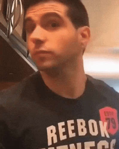 A Man Wearing A Black Reebok T-Shirt Is Making A Funny Face GIF