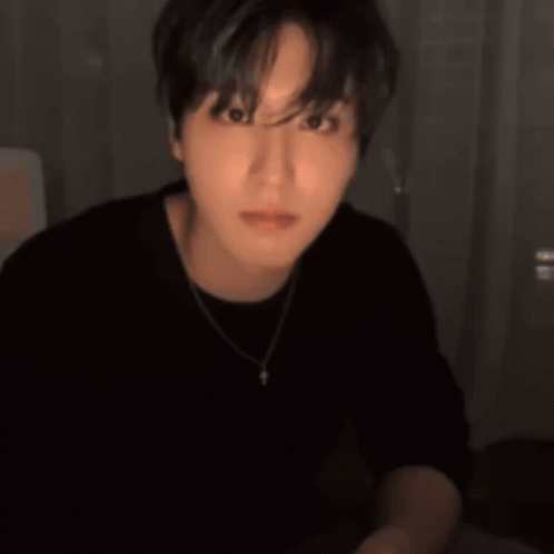 A Man Wearing A Black Shirt And A Necklace Is Smiling And Pointing GIF