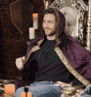 Man In Black Shirt And Purple Cape Sitting In Chair GIF