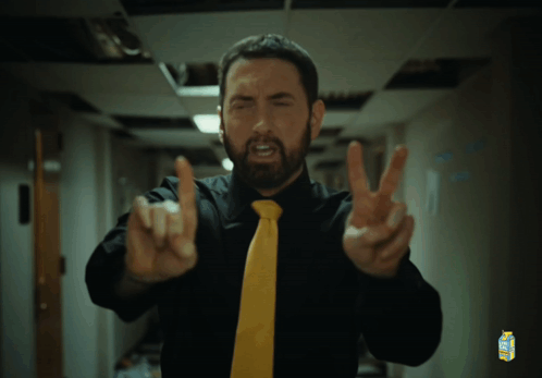 A Man Wearing A Black Shirt And A Yellow Tie Has A Carton Of Minute Maid On His Shirt GIF
