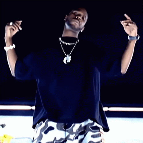 A Man Wearing A Black Shirt And White Camo Shorts Is Making A Peace Sign GIF