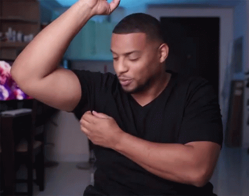 A Man Wearing A Black Shirt Is Flexing His Muscles GIF