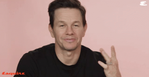 A Man Wearing A Black Shirt Is Giving A Peace Sign In Front Of An Esquire Logo GIF